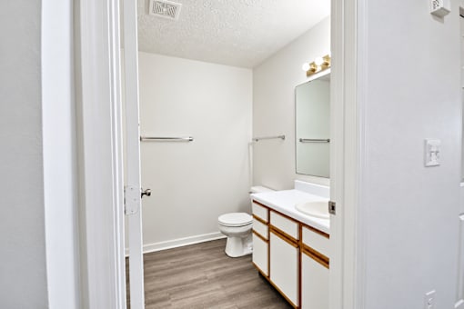 A white bathroom with a toilet, sink, and mirror.