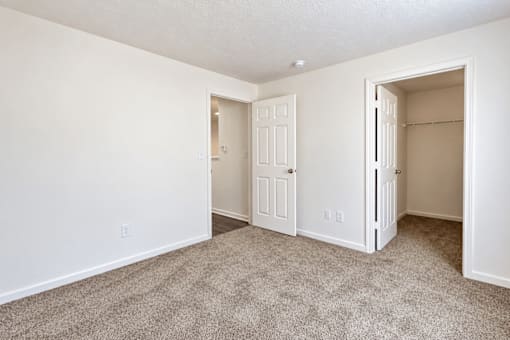 A room with a carpeted floor and two doors.