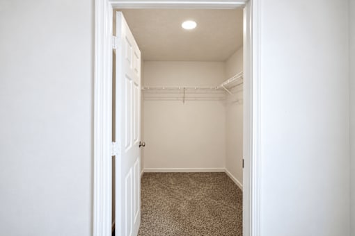 A white door is open to a small, carpeted room with a closet.