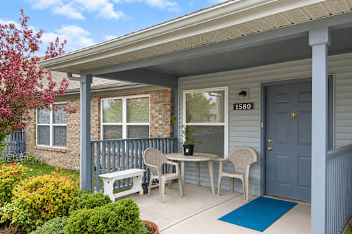 A small house with a porch and a blue door.