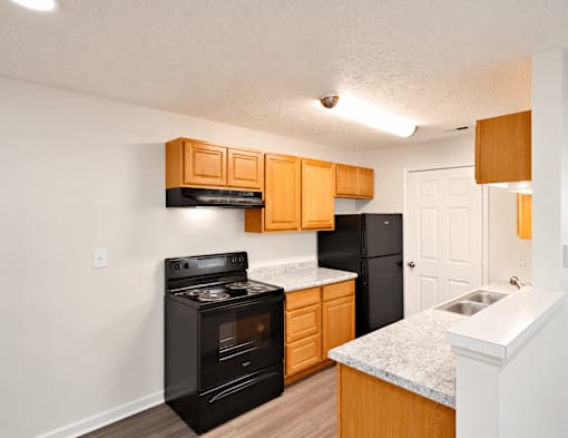 A kitchen with black appliances and wooden cabinets.