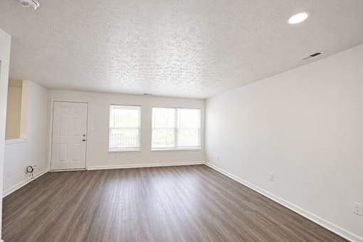 A room with a white ceiling, wooden floor, and a door.