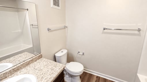 A white toilet sits next to a white shower in a bathroom.
