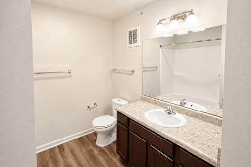 A white toilet sits in a bathroom with a sink and mirror.