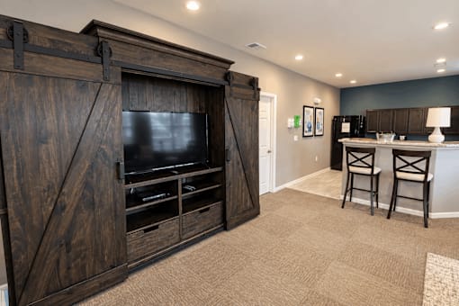 A room with a wooden entertainment center and a bar area.