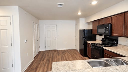 A kitchen with a black fridge and microwave.