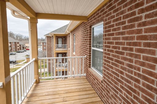 A balcony with a white railing and a brick wall.