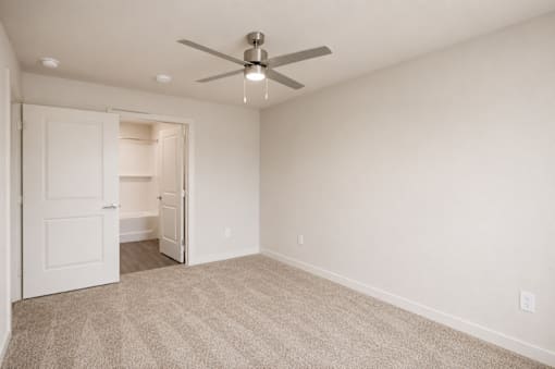A room with a ceiling fan and carpeted floor.