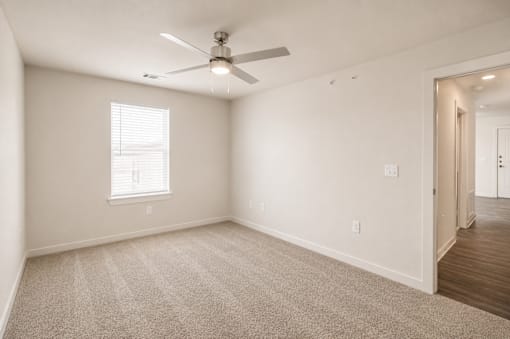 A room with a ceiling fan and a window with blinds.