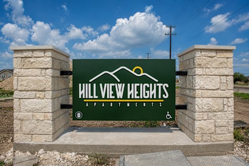 A sign for Hill View Heights Apartments is displayed on a stone pillar.