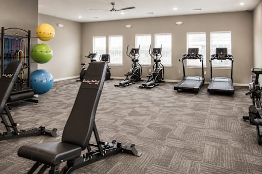 A gym with a variety of equipment including treadmills, exercise balls, and weight machines.