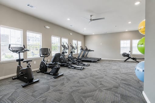 A spacious gym with a variety of exercise equipment and a ceiling fan.