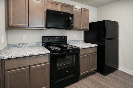 A kitchen with black appliances and brown cabinets.
