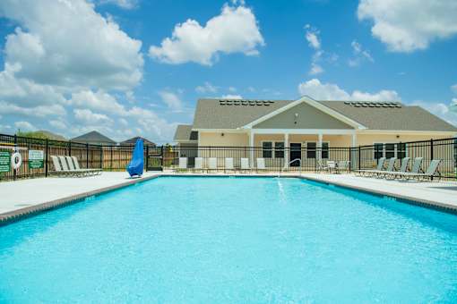 A large swimming pool in front of a building with a blue umbrella.