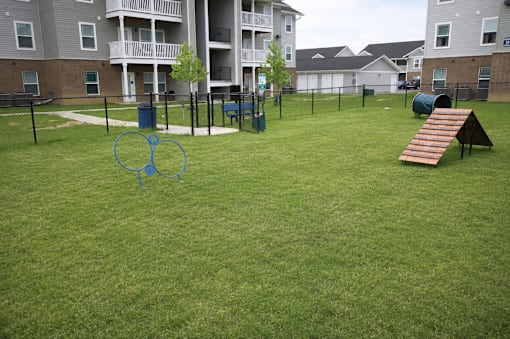 A playground with a slide and a seesaw in the middle of a grassy area.