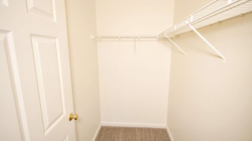 a walk in closet with a white closet door and a door to a closet