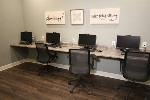 A room with four computers and two framed pictures on the wall.