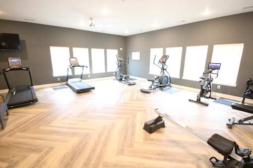 A gym with a variety of exercise equipment including treadmills, stationary bikes, and weight machines.