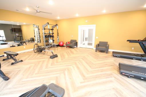 A spacious room with a wooden floor and a variety of exercise equipment.