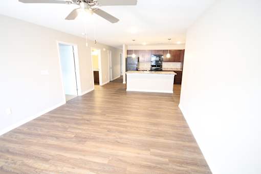 A spacious room with a ceiling fan and wooden flooring.
