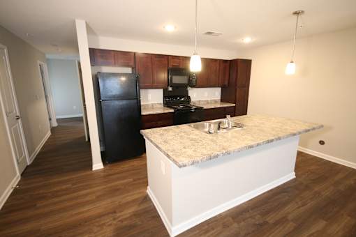 A kitchen with a black fridge and wooden cabinets.