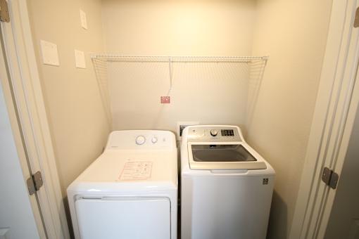 Two white front loading washing machines in a small laundry room.