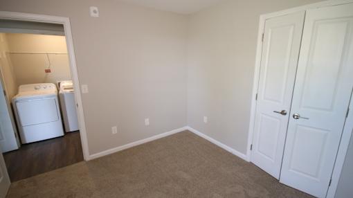 A room with a white door and a white fridge.