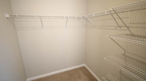 Empty shelves in a room with white walls and brown carpet.