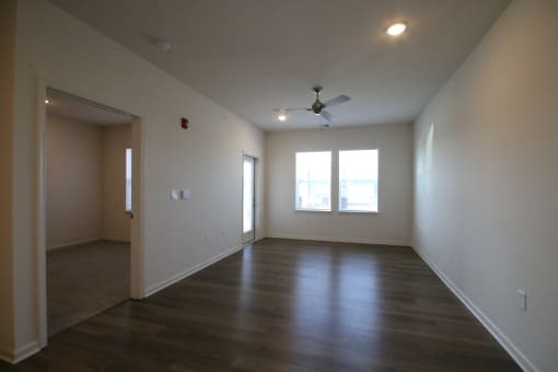 an empty living room with wood floors and a ceiling fan