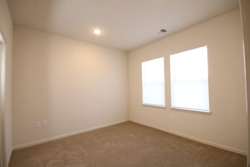 a living room with two windows and a carpeted floor
