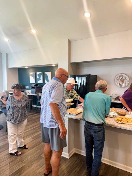a group of people standing around a buffet table in a room