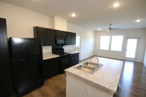 a kitchen with black appliances and granite counter tops in an empty apartment