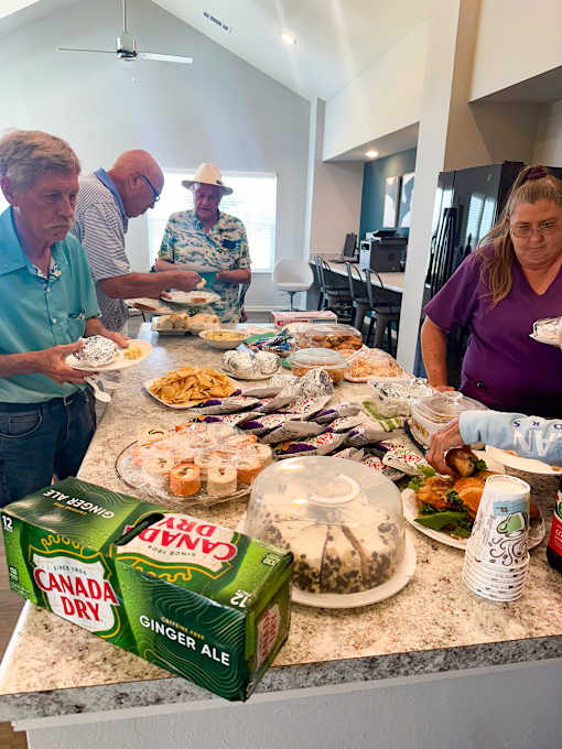 a group of people standing around a table with food
