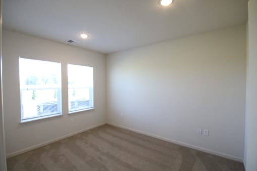 an empty living room with white walls and windows