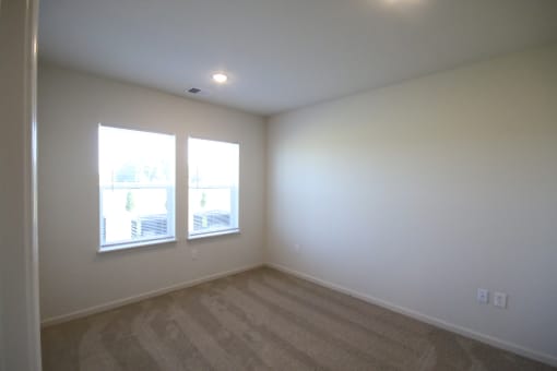 a living room with white walls and two windows
