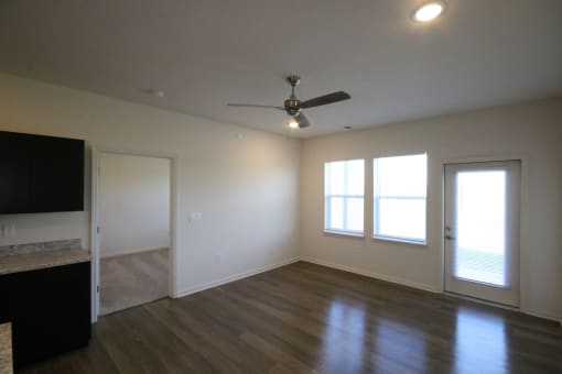 an empty living room with wood floors and a ceiling fan
