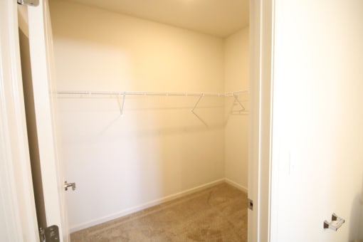 an empty closet with white shelves and a door