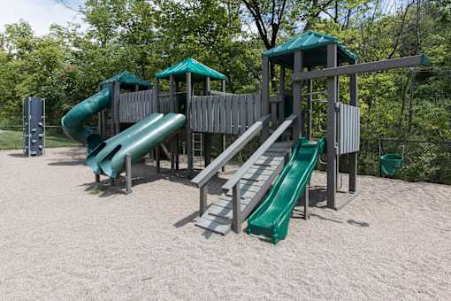 A playground with a green slide and a wooden structure.