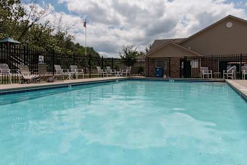 A swimming pool surrounded by lounge chairs and a fence.