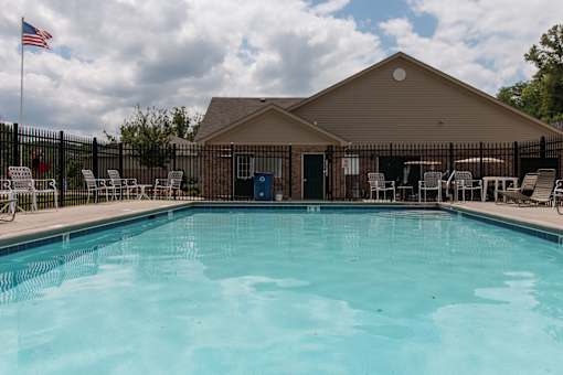 A pool in front of a building with a flag on the left.