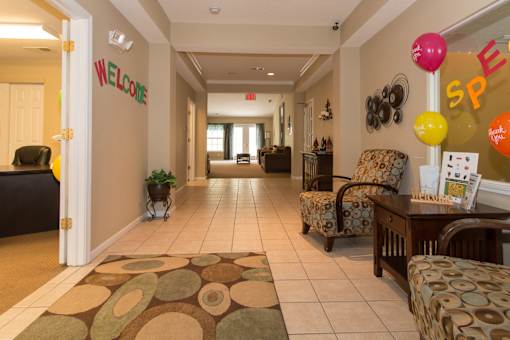 A hallway with a welcome sign and a chair with a pillow on it.
