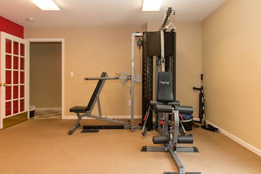 A home gym with a variety of equipment including a squat rack, a leg press machine, and a bench press.