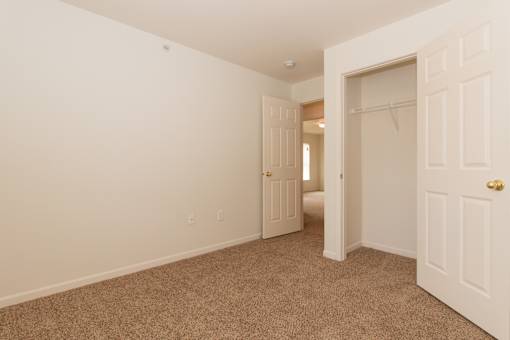 A room with a carpeted floor and two doors.
