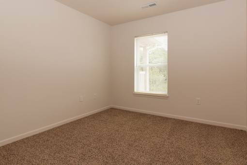 A room with a carpeted floor and a window.