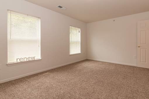A room with a carpeted floor and a window with blinds.
