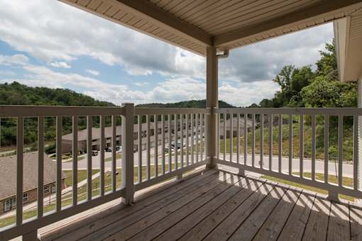 A wooden deck with a white railing overlooks a residential street.