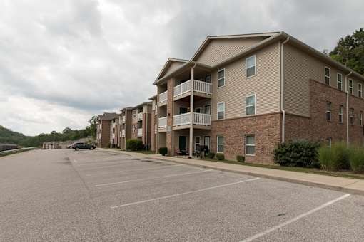A parking lot in front of a brick apartment building.