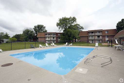A swimming pool surrounded by a black fence and chairs.