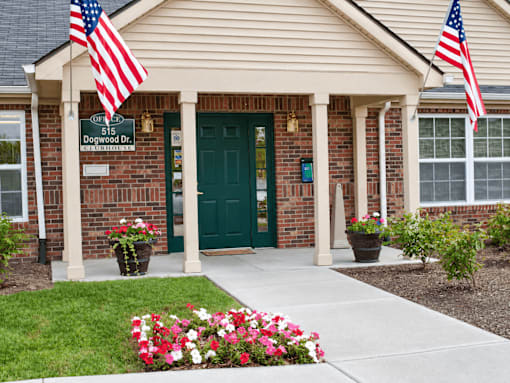 A house with a green door and two American flags on either side.