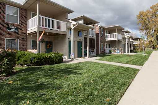Apartment complex with green lawn and trees.
